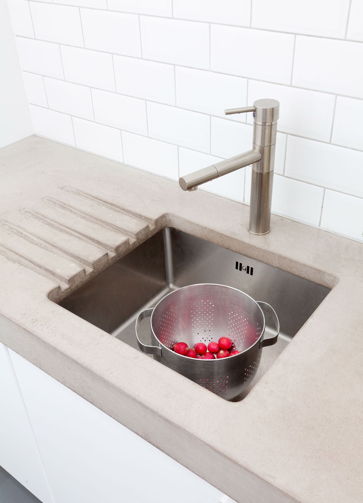 A kitchen sink with a concrete countertop.