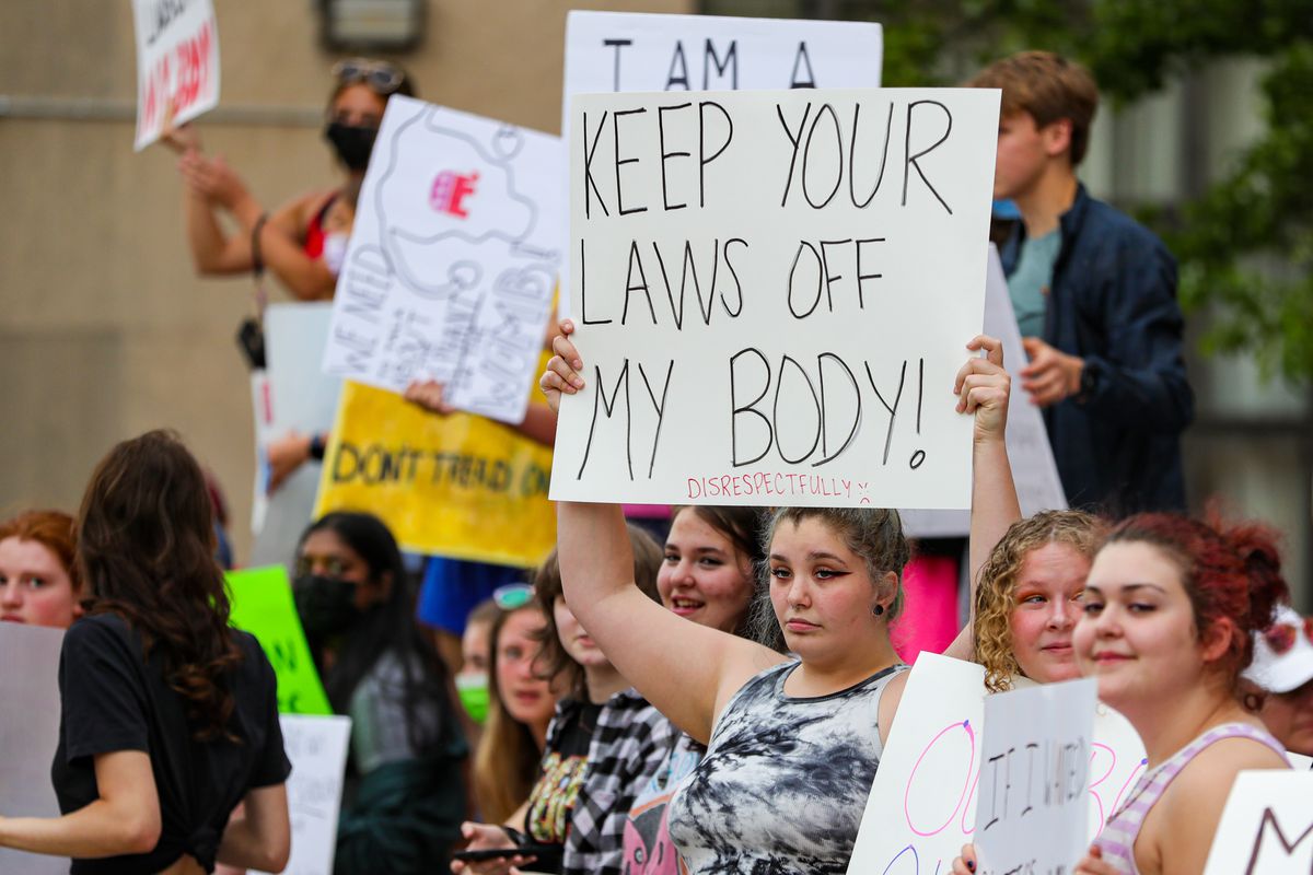 A protester in a crowd holds up a sign that reads, “Keep your laws off my body!”
