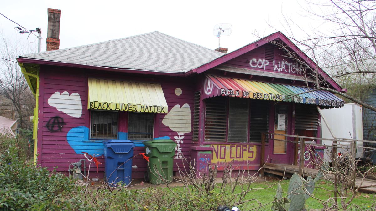 A purple bungalow painted with yellow and rainbow awnings.