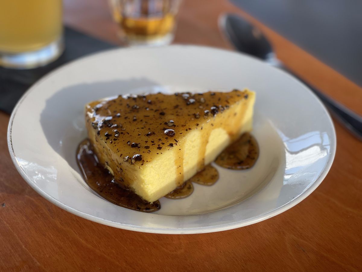 A parmesan cheesecake, drizzled with honey and pepper flakes, on a plate.