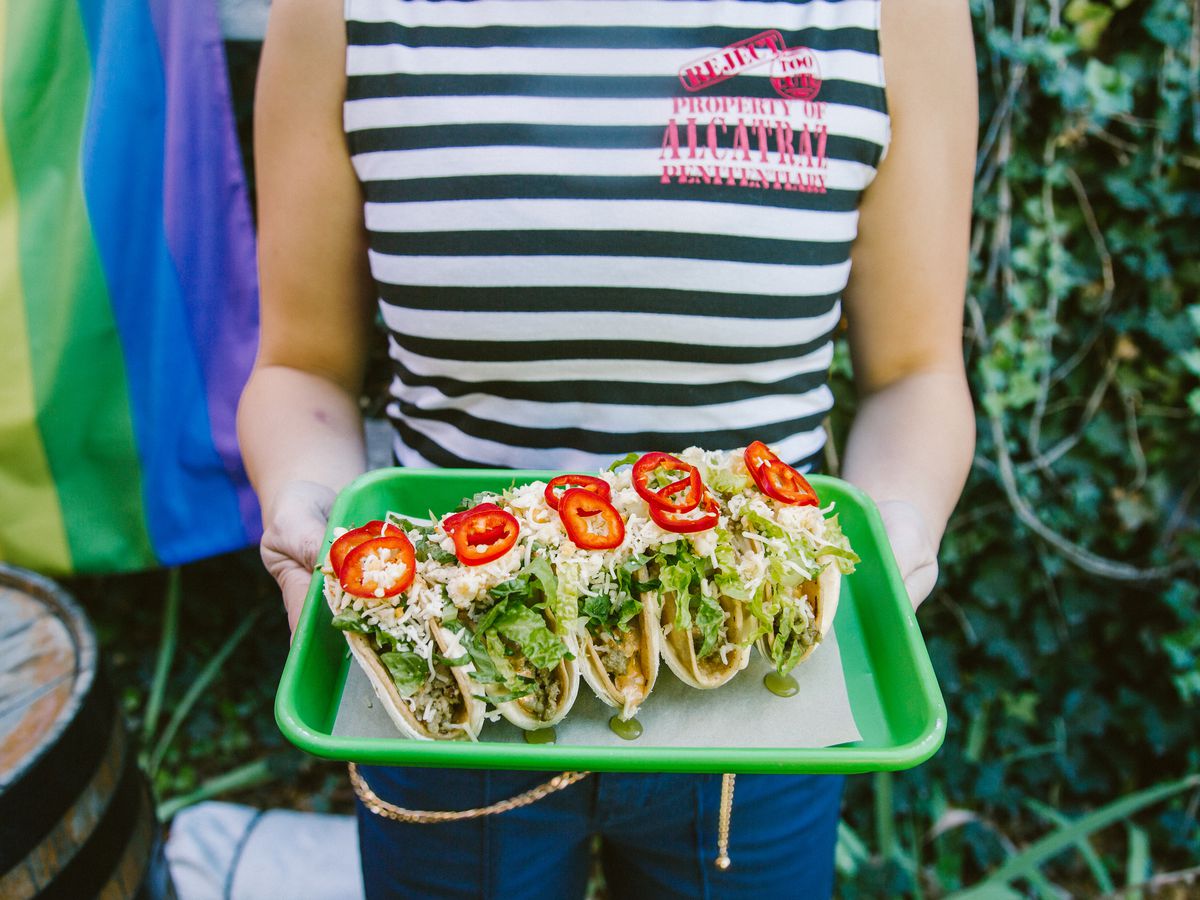 Person holding a green tray of tacos from Mister Oso.