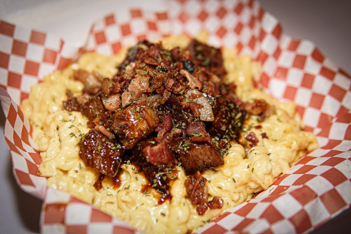 A basket of macaroni and cheese topped with a pile of smoked brisket.