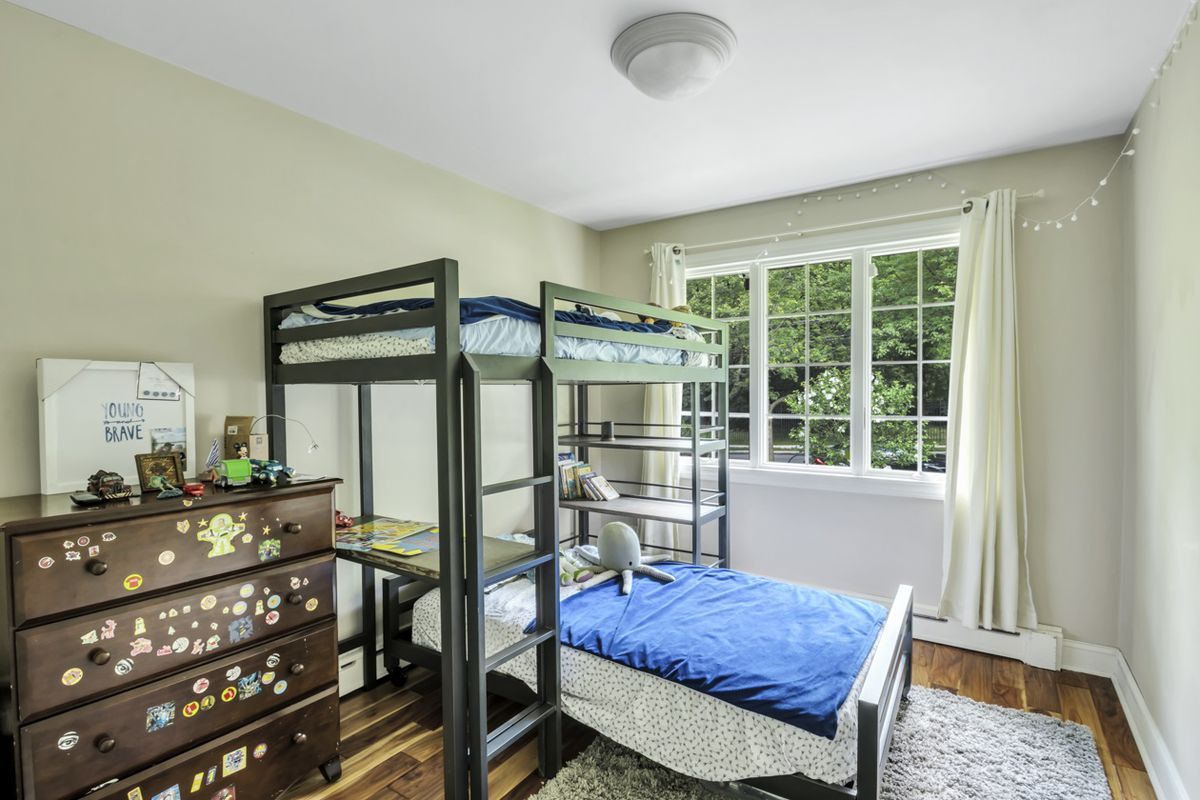 A bedroom with a large window, base moldings, and a bunk bed.