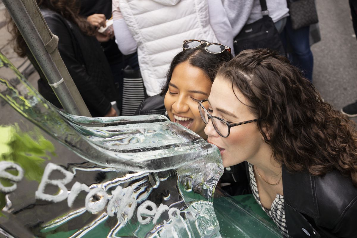 Two women take brine from an ice luge
