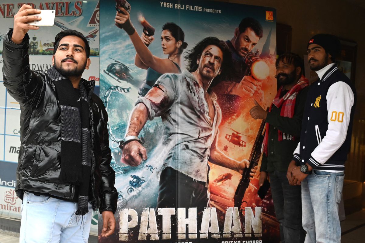 Moviegoers take their pictures in front of a poster of the Bollywood movie ‘Pathaan’ at a cinema hall in Amritsar.