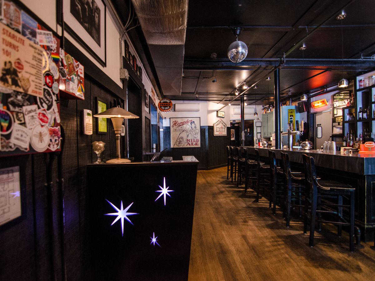 A view into a bar, starting with a star-spangled host stand. A disco ball hangs from the ceiling.