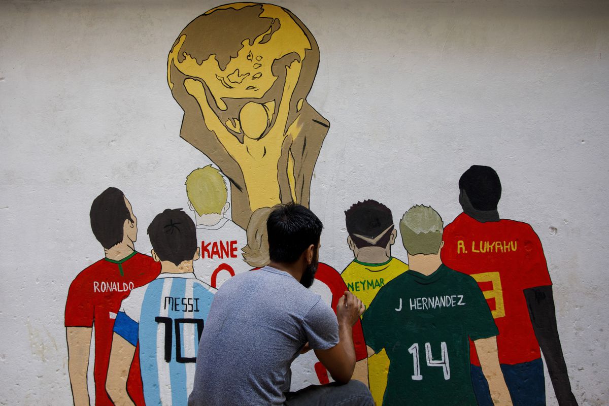 An artist paints a wall with the Fifa world cup trophy to...