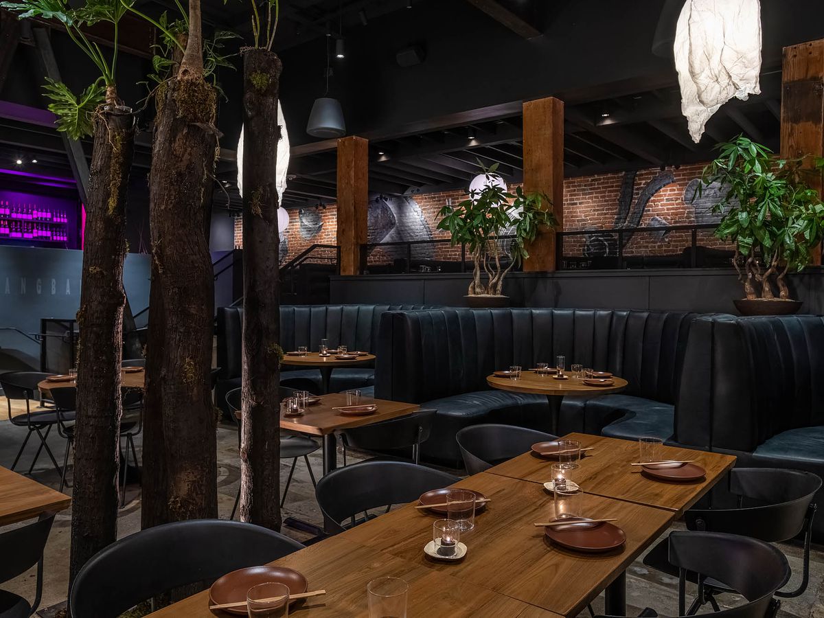 A dark dining room with rounded booths, low lights, at LA restaurant Yangban.