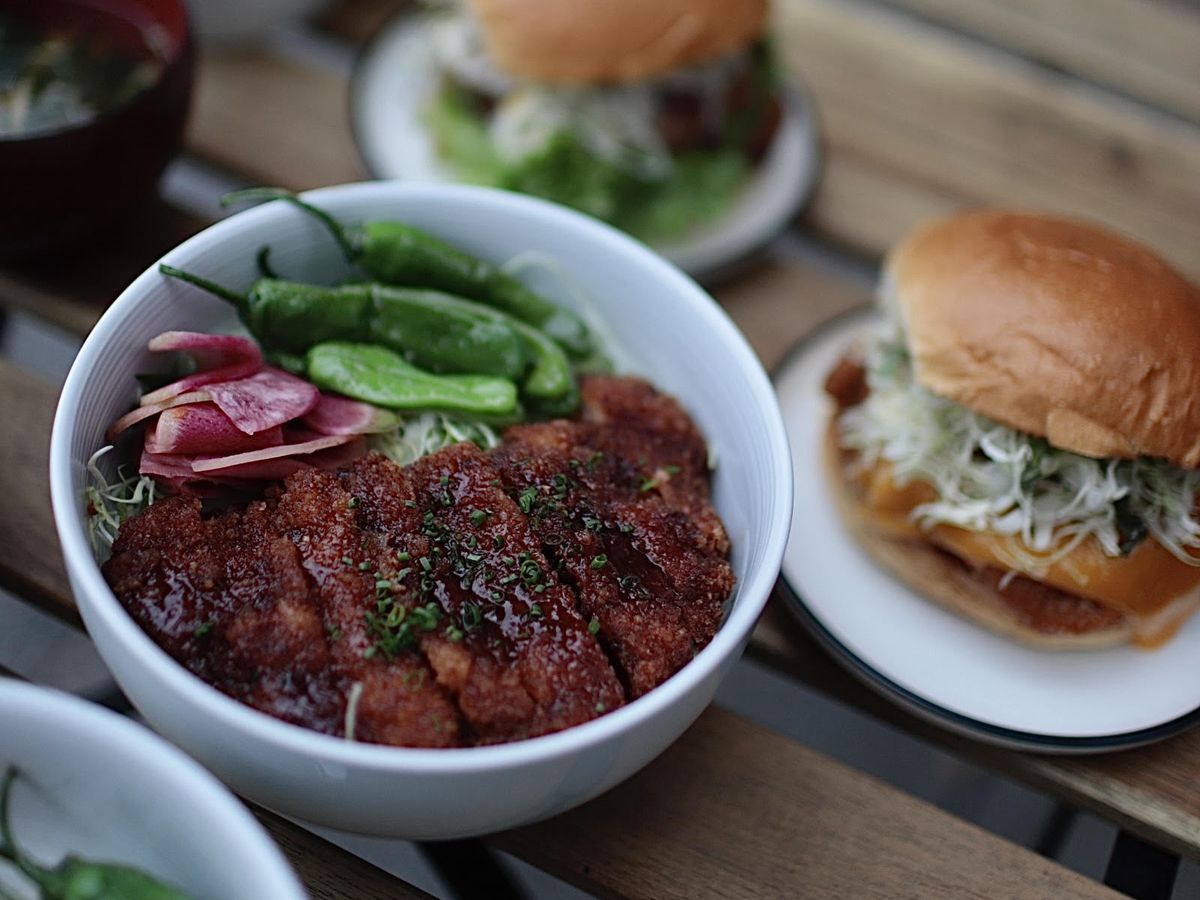 Bowls and katsu sandwiches at Chef Katsu laid out on a wooden picnic table.