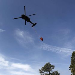 A U.S. Army helicopter delivers a load of water to the Black Forest wildfire, north of Colorado Springs, Colo., on Thursday, June 13, 2013.  The blaze in the Black Forest is now the most destructive in Colorado history, surpassing last year's Waldo Canyon fire, which burned 347 homes, killed two people and led to $353 million in insurance claims.  (AP Photo/Brennan Linsley)