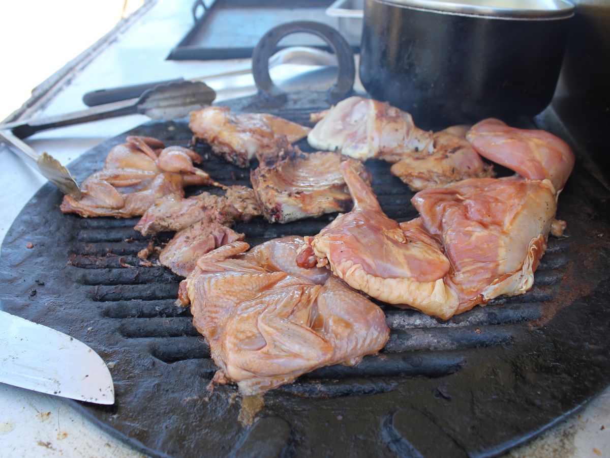 Cuts of quail and rabbit on a small grill with grilling tools