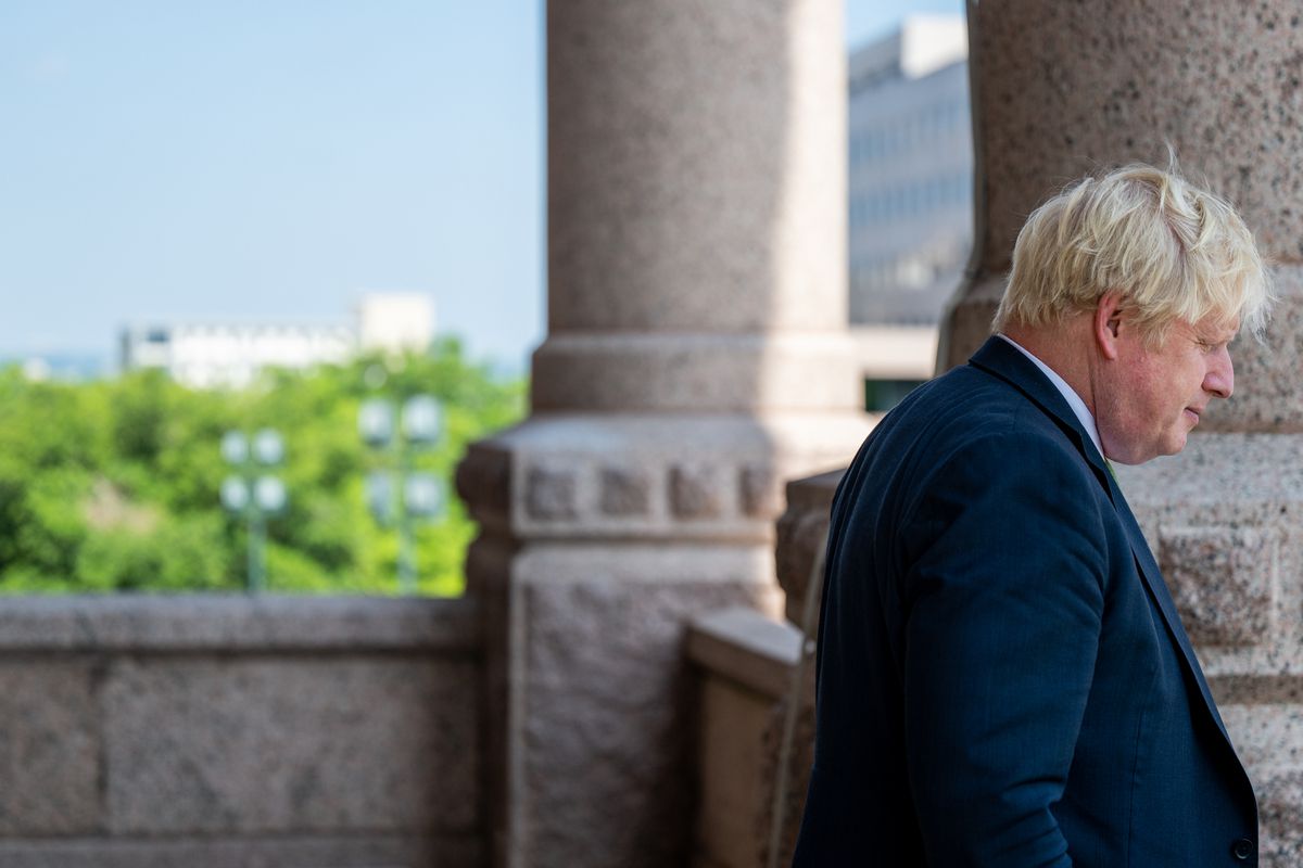 Boris Johnson stands on a balcony with large stone columns
