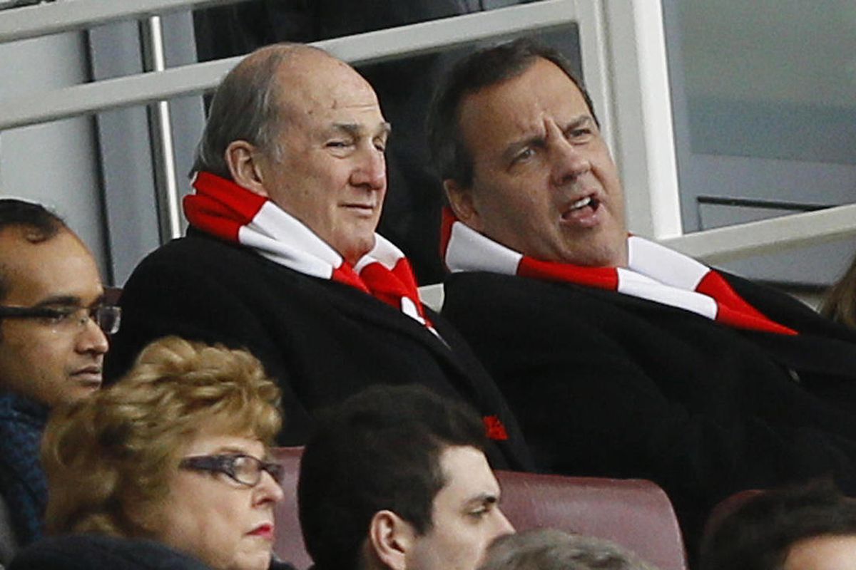 New Jersey Gov. Chris Christie, right, wearing an Arsenal scarf, sits with Rutgers University President Robert Barchi in the stands during the English Premier League soccer match between Arsenal and Aston Villa at the Emirates stadium in London, Sunday, F