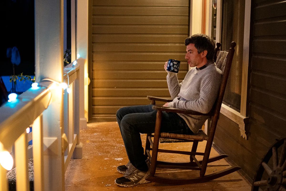 Nathan in a rocking chair, sitting on a porch.