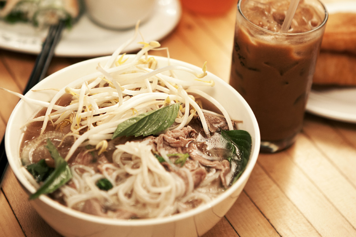 A bowl of pho at Pho Bac Sup Shop with iced coffee on the side.