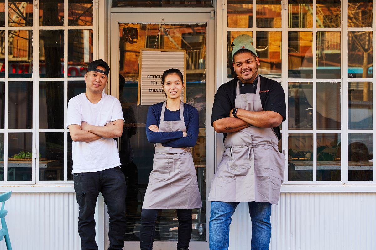 Three people pose for a picture outside the front door of their restaurant