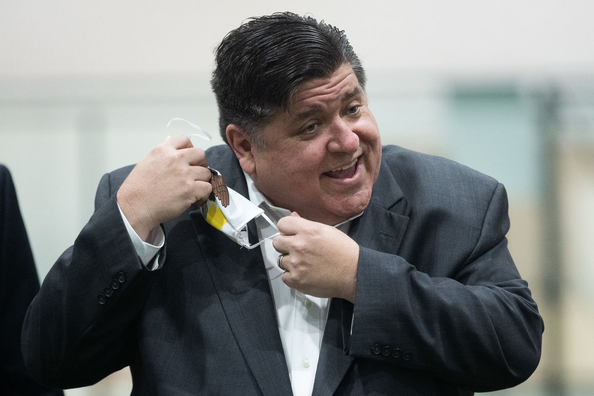 Gov. J.B. Pritzker takes off his mask before speaking to the media during an event in the Pullman neighborhood in October.