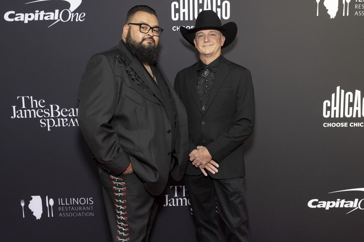 Two men pose on a red carpet.