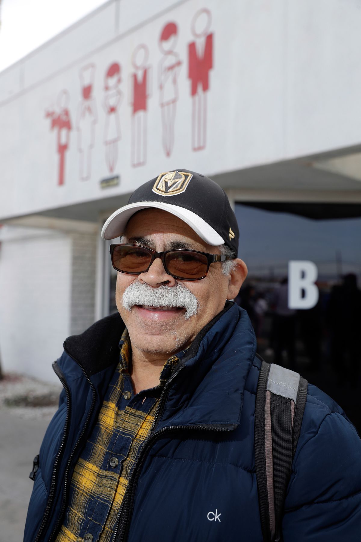 A man wearing sunglasses and a cap, with a neat mustache, poses outside the Culinary Union hall.