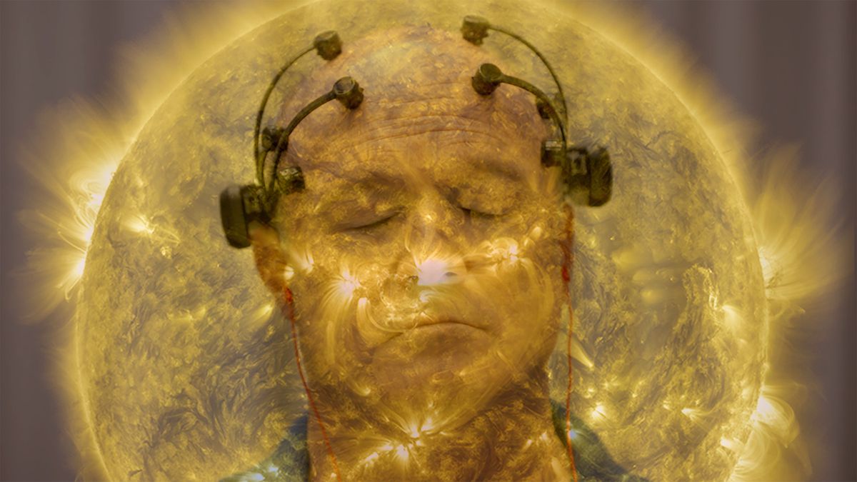 A bald man with his eyes closed and electrodes on his head, superimposed with a glowing close-up image of the surface of a sun