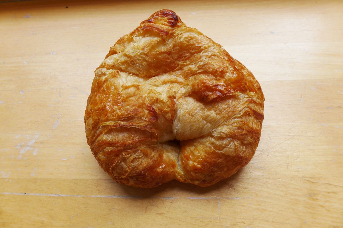 A round croissant on a wooden background.