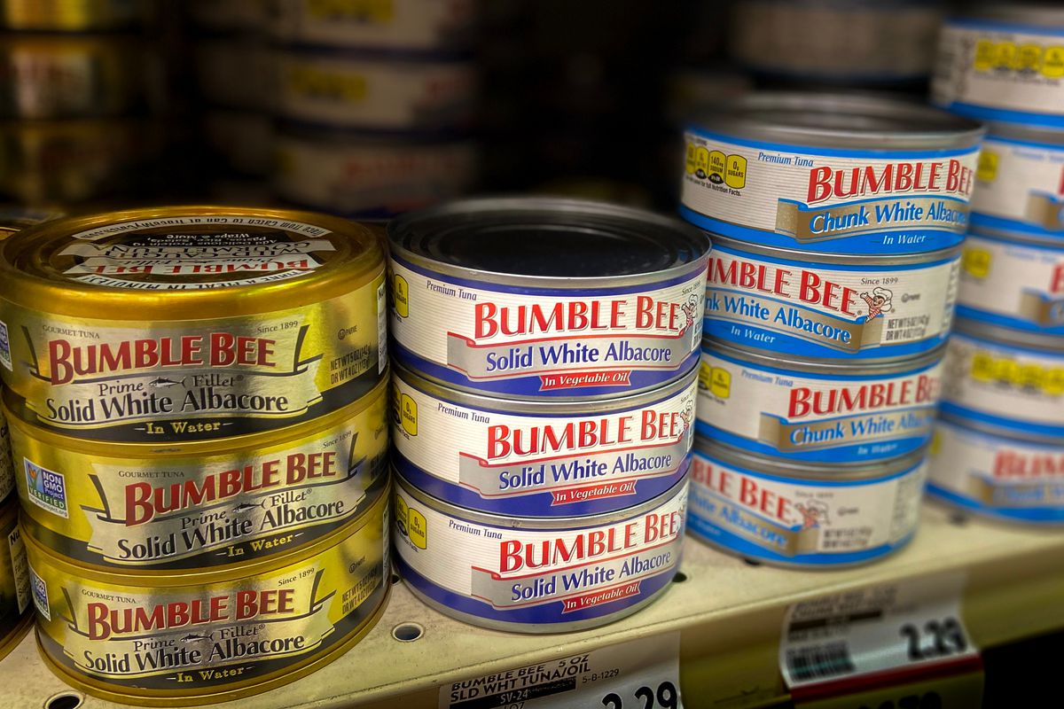 Stacks of Bumble Bee canned tuna on a grocery store shelf.