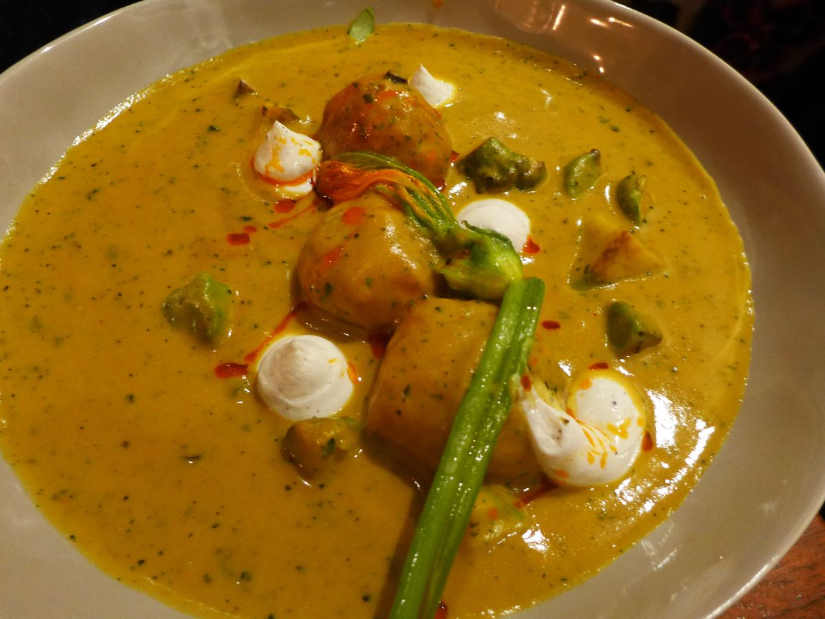 Wads of kofta dumplings are submerged in a brown gravy with dabs of white whipped paneer.