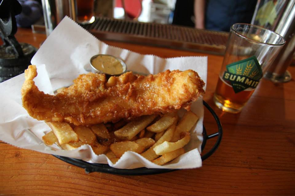 A basket of fish and chips on a wooden table. 