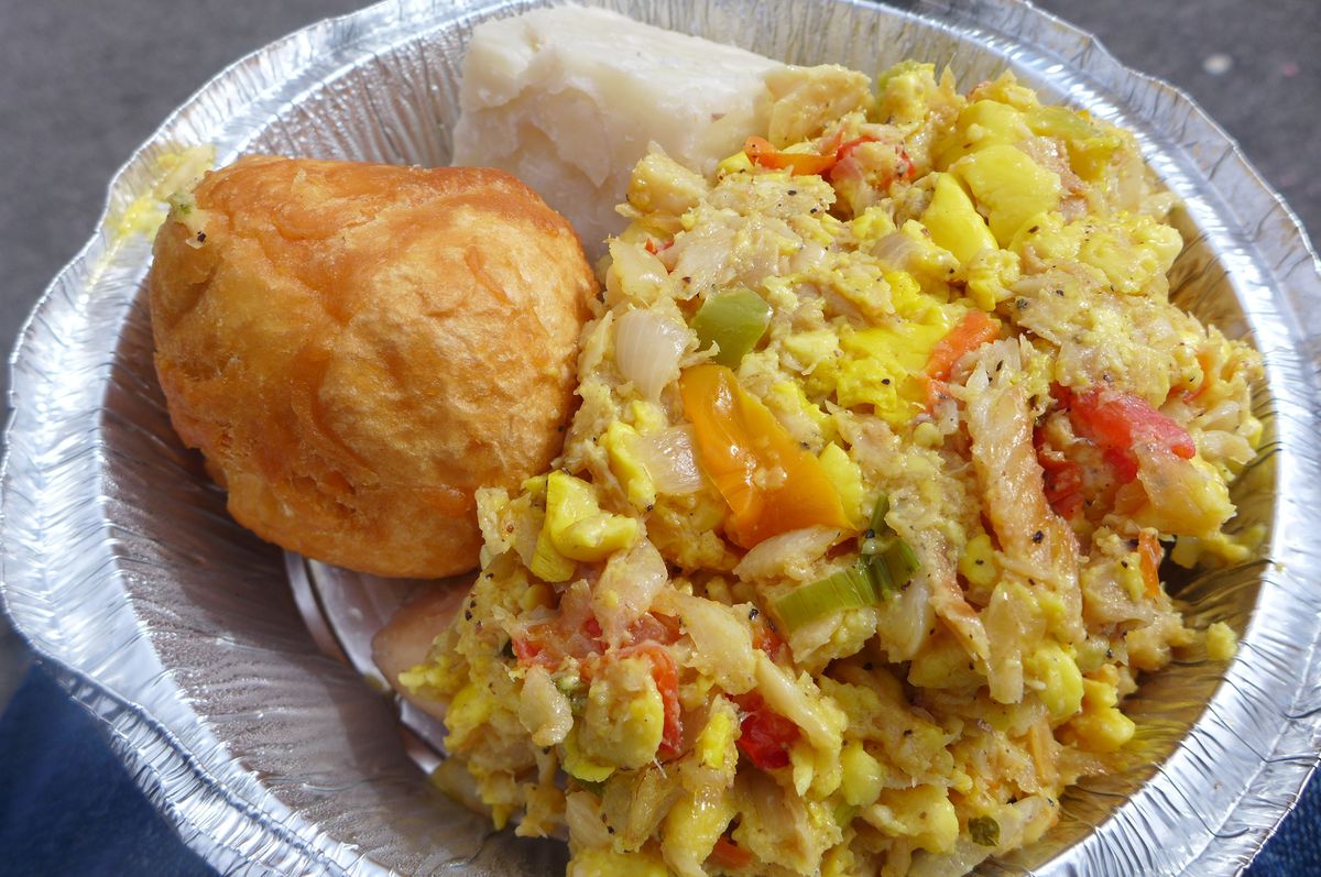 A metal container with something that looks like scrambled eggs and peppers, with a big fried dumpling on the side.