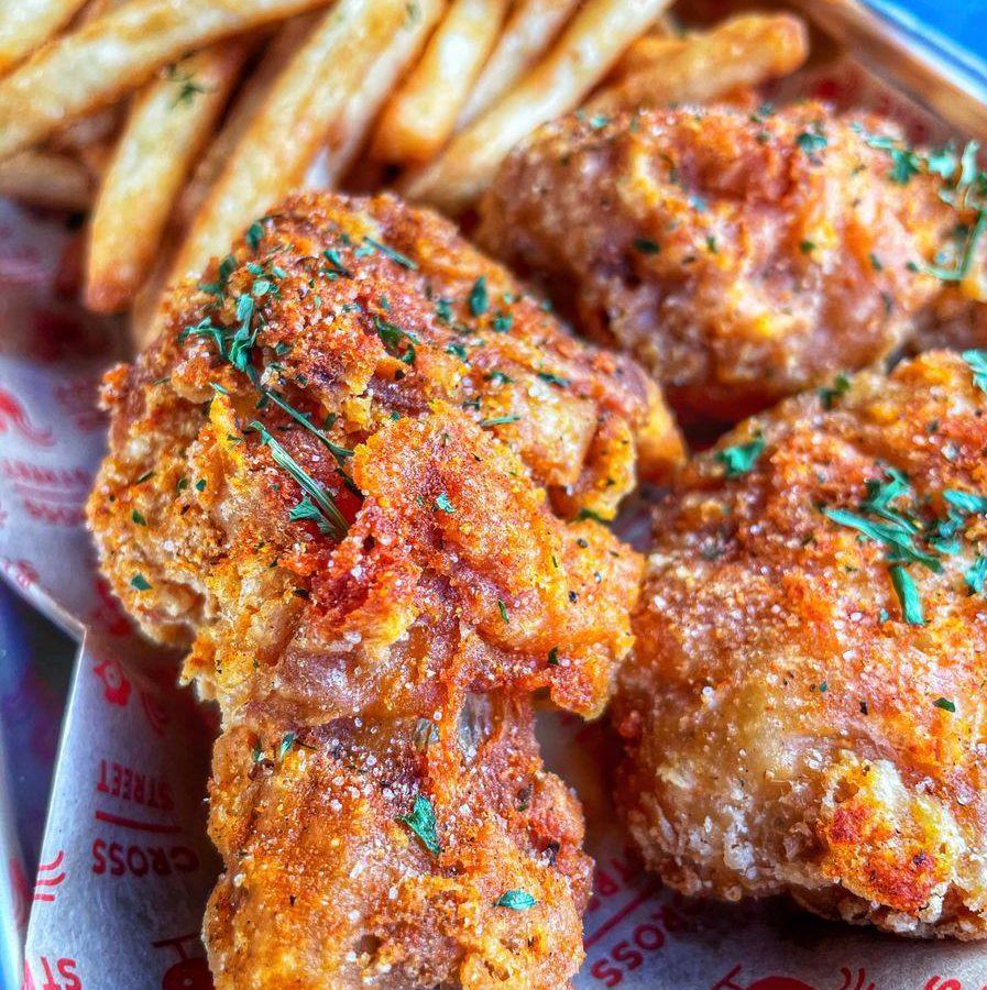 Rimmed pan filled with Fried chicken and French fries.