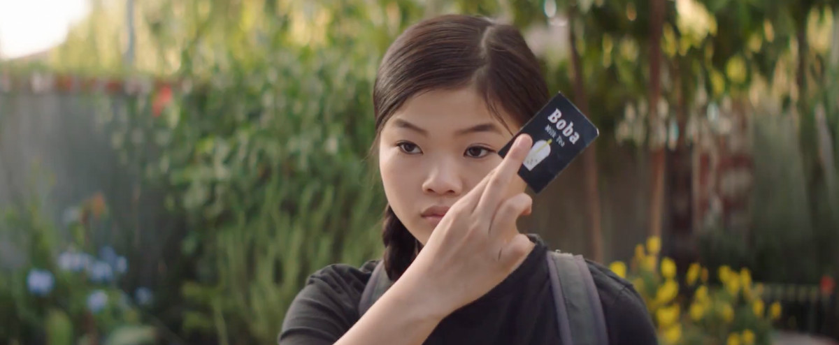 a girl in black holds up a boba card
