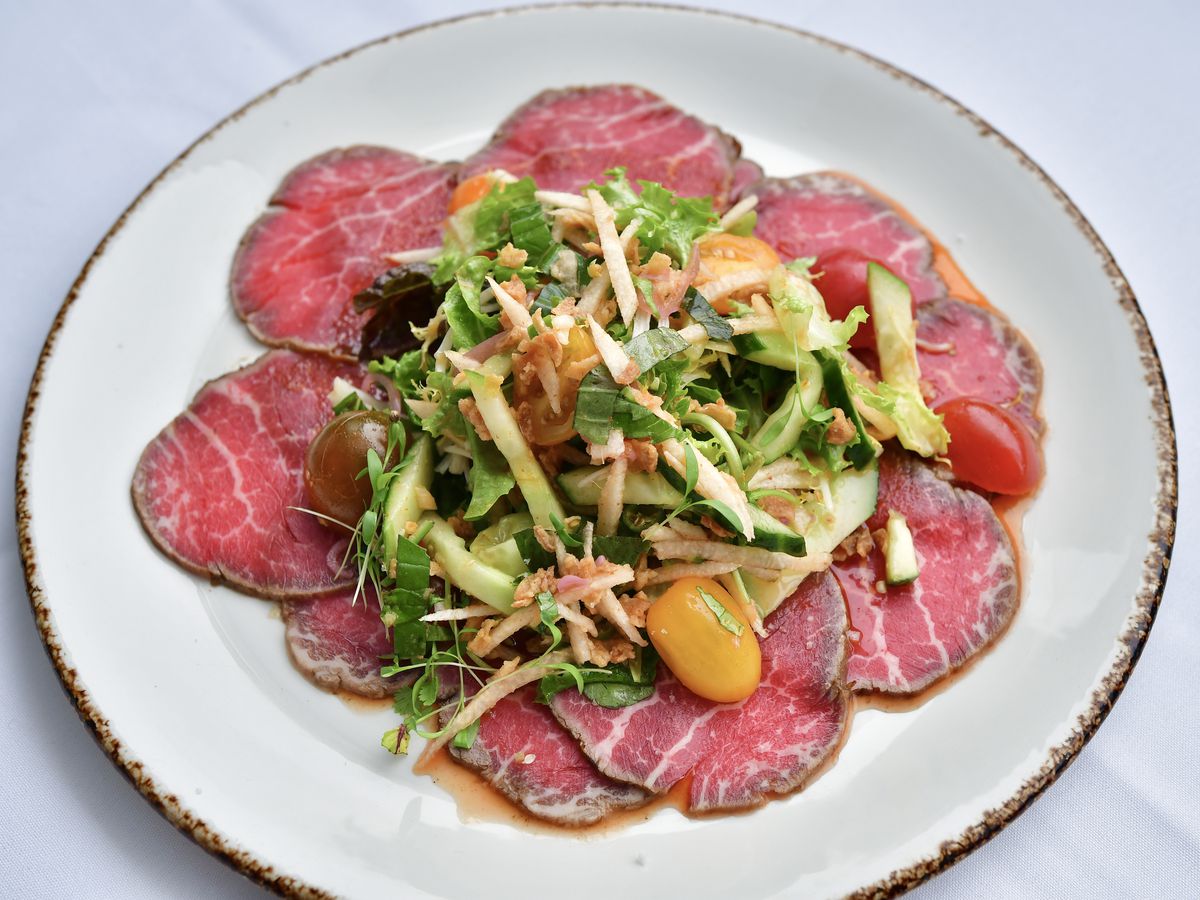 thin slices of rare prime beef tenderloin, topped with shredded cucumbers, greens, and tomato at Le Colonial.