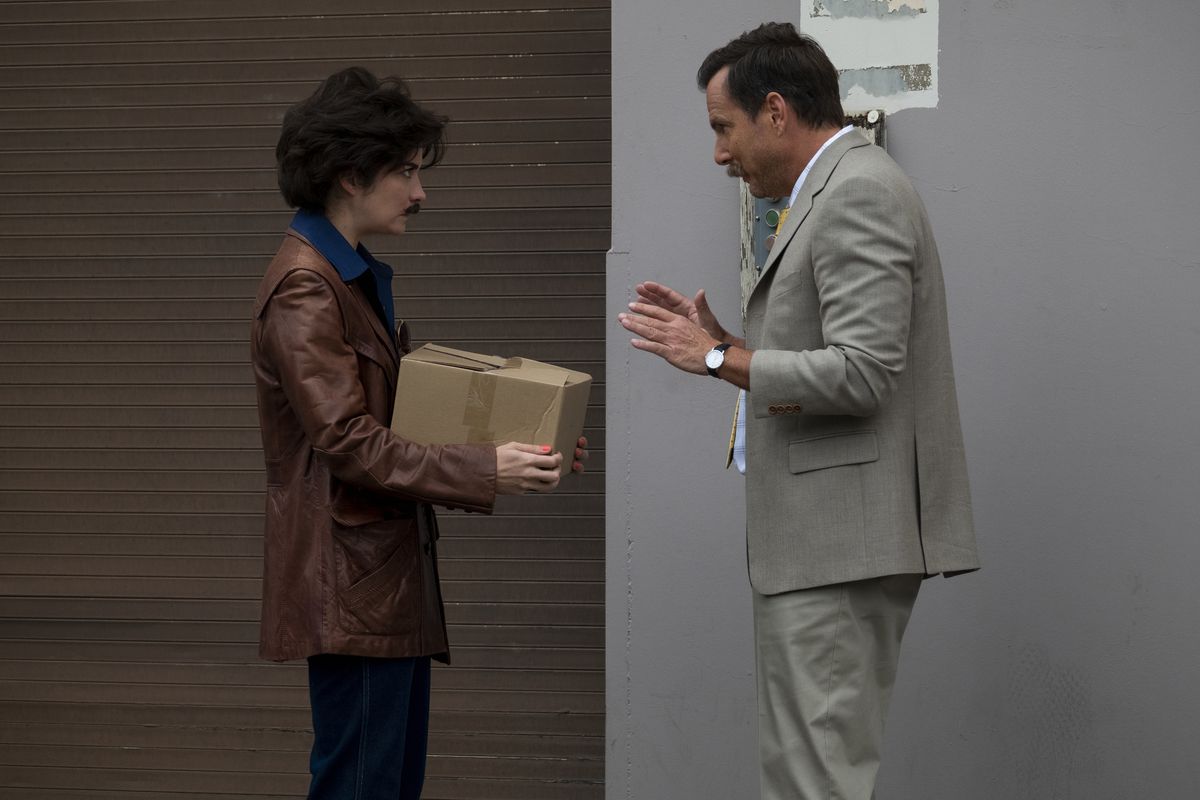 Annie Murphy and Will Arnett in a still from Murderville; the former undercover dressed like a man holding a box