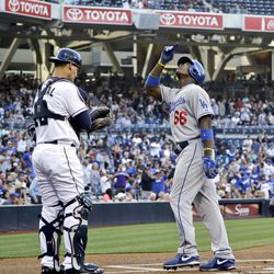 Los Angeles Dodgers' Yasiel Puig points skyward as he crosses home plate in front of San Diego Padres catcher Yasmani Grandal after his solo homer during the first inning of a baseball game in San Diego, Thursday, June 20, 2013. 