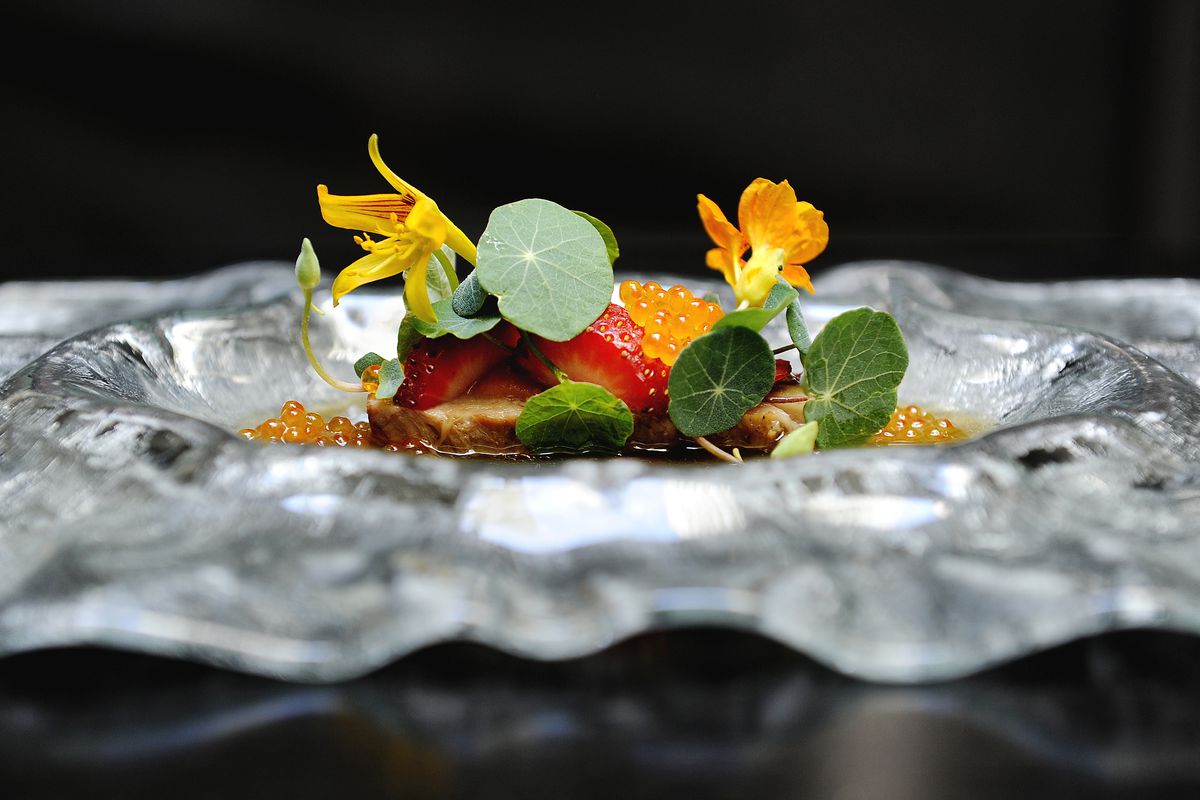 A bright fine dining dish, served on a wavy plate, with nasturtium and citrus.