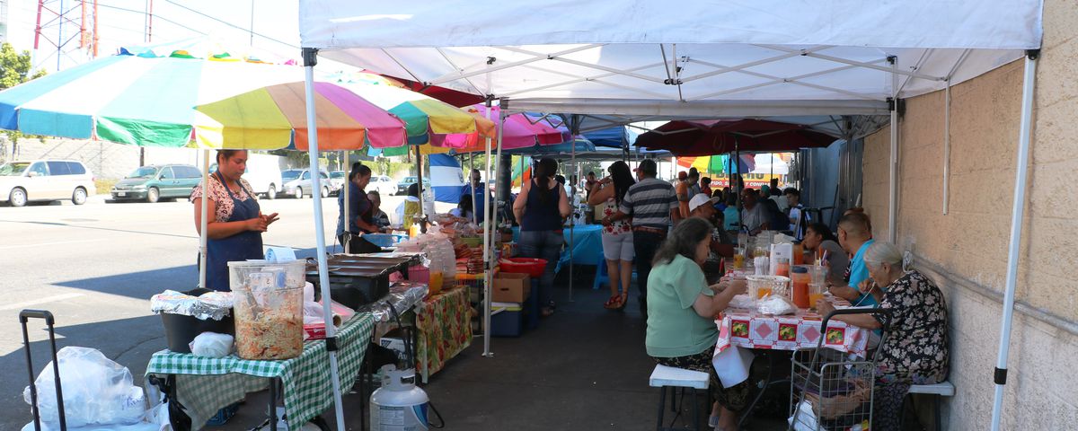 Salvadoran street market in front of Koreatown’s Two Guys Plaza with stalls and cooked foods.