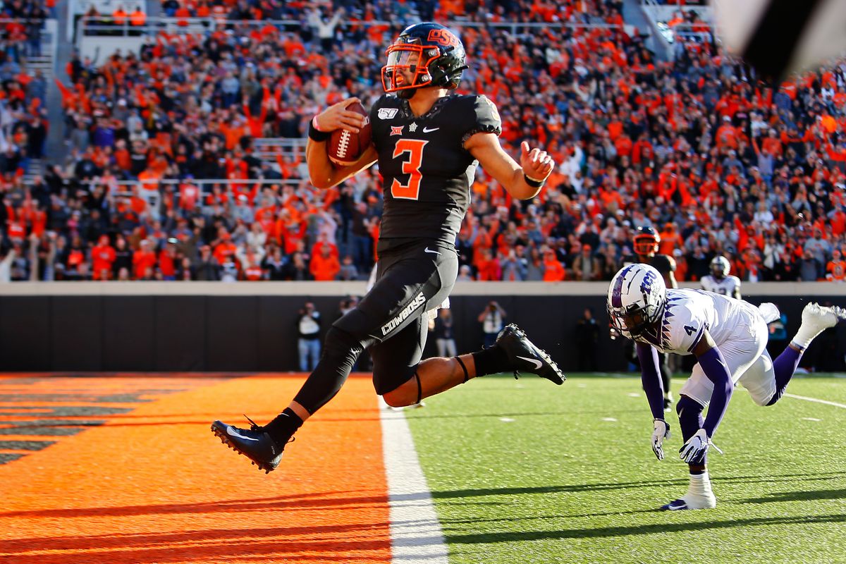 Quarterback Spencer Sanders of the Oklahoma State Cowboys leaps into the end zone for a 43-yard touchdown against safety Keenan Reed of the TCU Horned Frogs only to have it called back for an illegal shift in the fourth quarter on November 2, 2019 at Boone Pickens Stadium in Stillwater, Oklahoma.