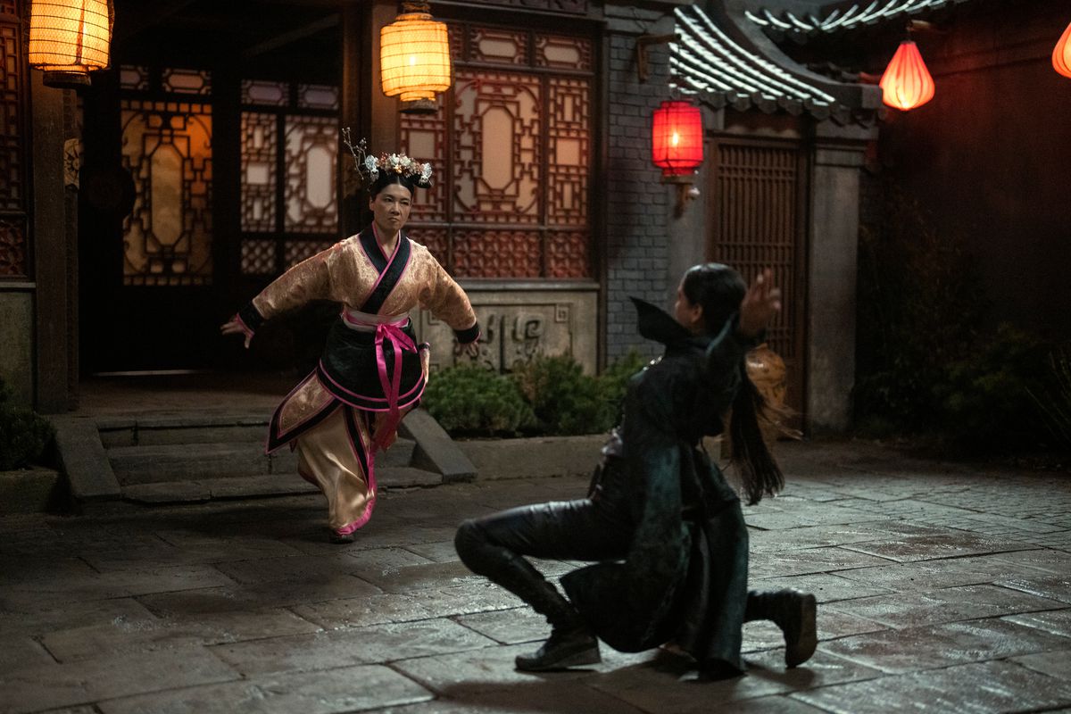 inej affronte une femme portant des vêtements d'inspiration chinoise dans une cour ouverte