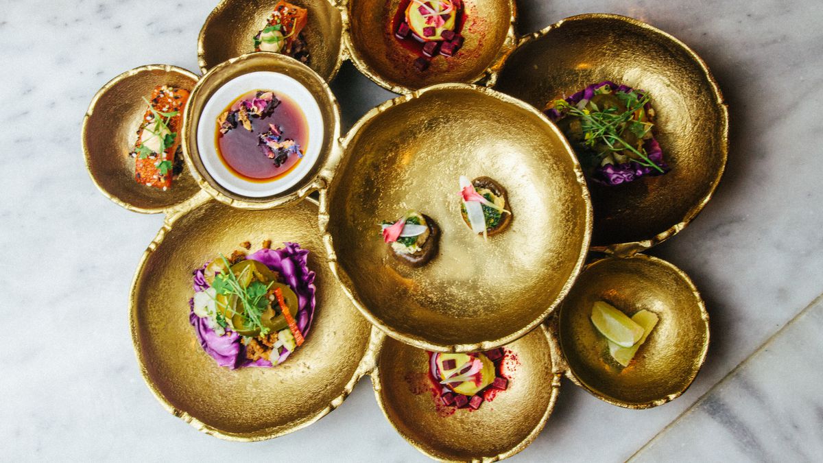 A collection of gold dishes stacked like a flower with small bites on each.