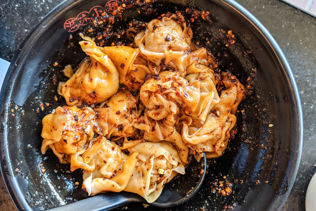 Spicy sauced wontons at Mian restaurant in a dark bowl.