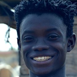 A young man at grilling fish at a wharf in Greater Accra smiles.