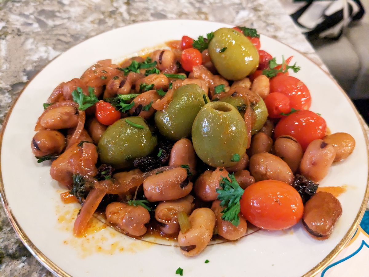 A plate of beans, baby plum tomatoes, and green olives.