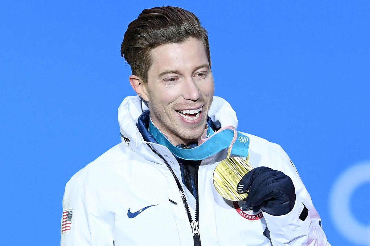 Snowboarder Shaun White smiles and holds up his 2018 Olympic gold medal.