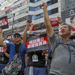 Protesters gesture while holding placards reads "Form an independent investigation on legislative committee" during a march in Hong Kong, Sunday, July 21, 2019. Thousands of Hong Kong protesters marched from a public park to call for an independent investigation into police tactics.(AP Photo/Vincent Yu)