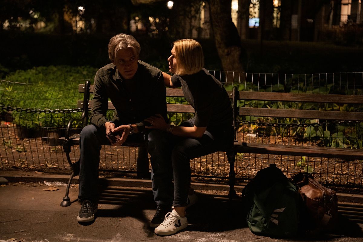Derek (Timothy Olyphant) sitting on a park bench at night looking dejected while Sam (Claire Danes)  comforting him. Nearby is two dufflebags (which are full of money, though you can’t see it)
