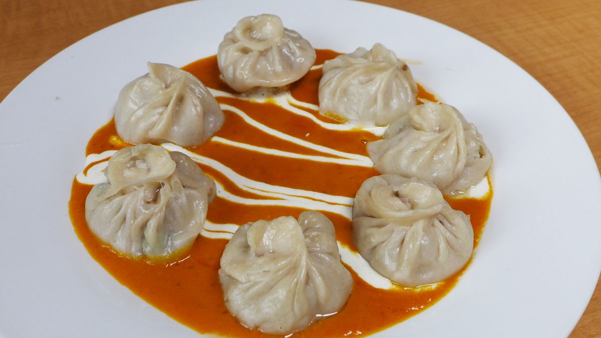 Seven dumplings napped with red and white sauce.