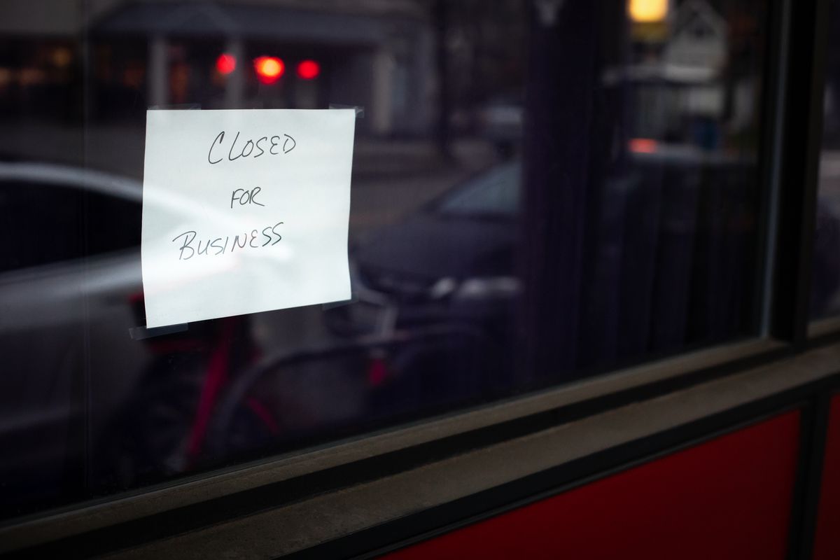 Hand written “Closed for Business” sign in the dark window of a shut down restaurant, with space for text on the right 