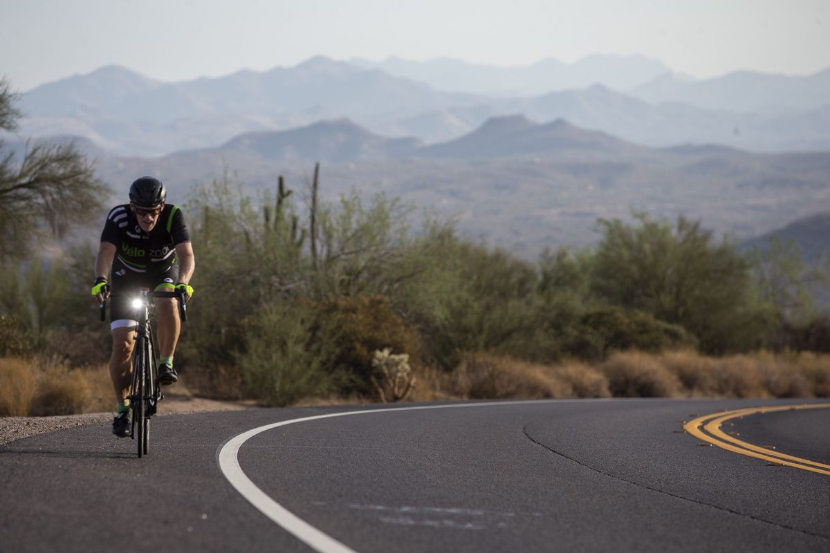 A cyclist rides his bike on Usery Pass Road along Usery Mountain Regional Park and Tonto National Forest in Mesa on July 18, 2021.