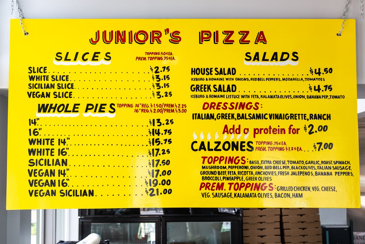The yellow menu hanging above the cash register at Junior’s Pizza