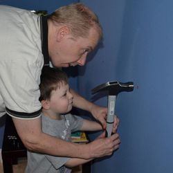 Niels de Jong's son helps him set a drywall anchor to install shelves in their new home in Ohio.